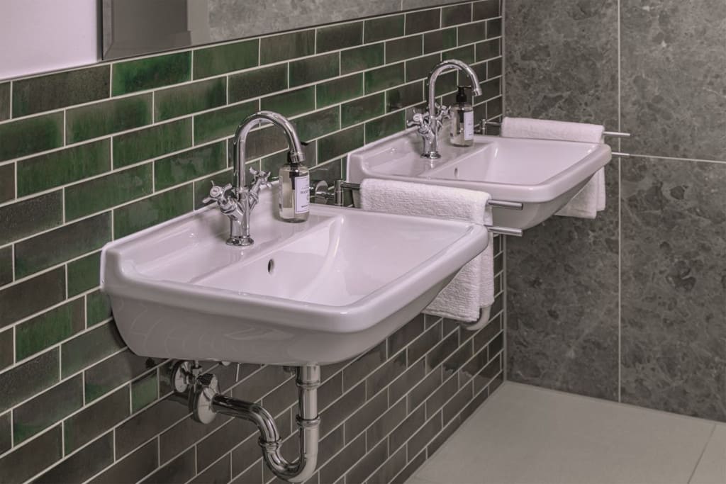 Zielone płytki, zaczerpnięte z budynku tarasu Junghans, nadają łazience nostalgiczny charakter. W połączeniu z szarymi marmurkowymi płytkami tworzą połączenie tradycji i nowoczesności.