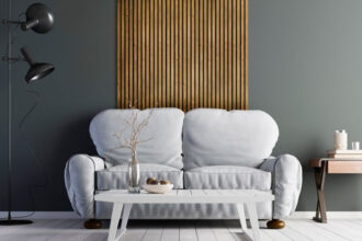 Lamele dekoracyjne ścienne w salonie, na pierwszym planie szara, wygodna kanapa.