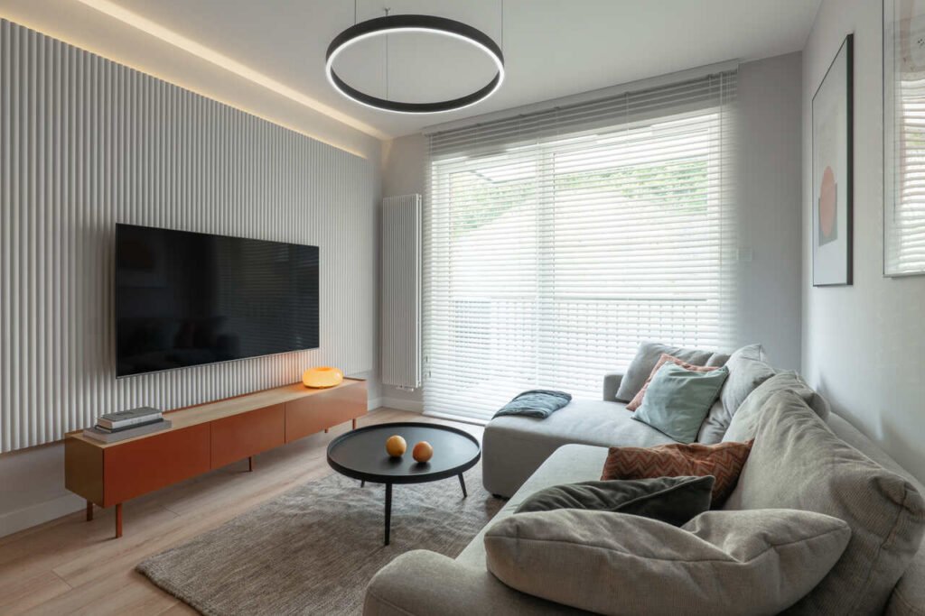 W salonie otwartym na kuchnię panuje styl eklektyczny. Stonowana kolorystyka bazuje na szarościach z wyrazistym akcentem, proj. KODO.