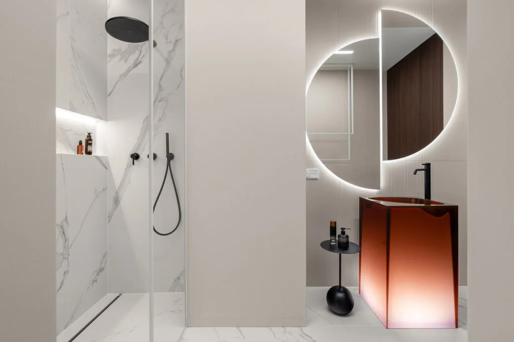 Łazienka gościnna w apartamencie wakacyjnym w inwestycji Brabank w Gdańsku. Połączenie klasycznego wzoru marmuru callacata z delikatnym odcieniem beige na ścianach. Całość to doskonałe i ponadczasowe tło dla pięknej podświetlanej umywalki i luster marki Antonio Lupi. Fot. Katarzyna Seliga-Wróblewska, Marcin Wróblewski / Fotomohito.