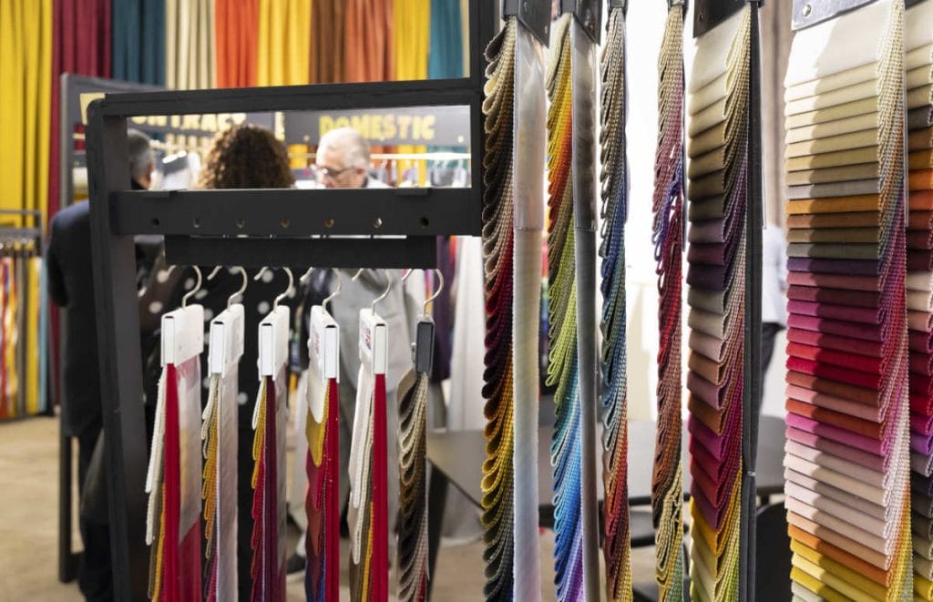 Tkaniny różnokolorowe na wieszakach na targach Heimtextil