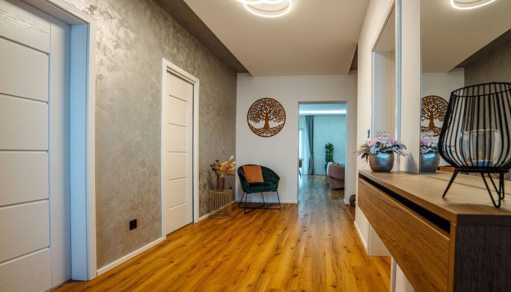 Wnętrze w nowoczesnym stylu, tynk betonowy na ścianach, nowoczesne oświetlenie, białe drzwi, panele podłogowe drewniane.