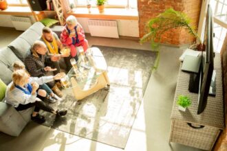 Rodzina przy posiłku na szarej kanapie przed telewizorem