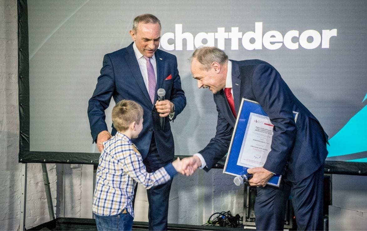 Jan Szynaka i prezes Schattdecor stoją na scenie z wnukiem Jana Szynaki podczas jubileuszu firmy