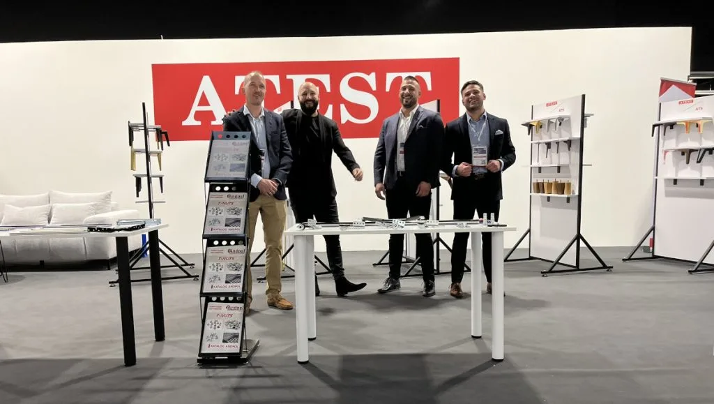 Ekipa firmy na stoisku ATEST i ATS z ekspozycją nóg meblowych, akcesoriów i rozwiązań meblowych podczas targów Warsaw Home 2024 w hali wystawowej.