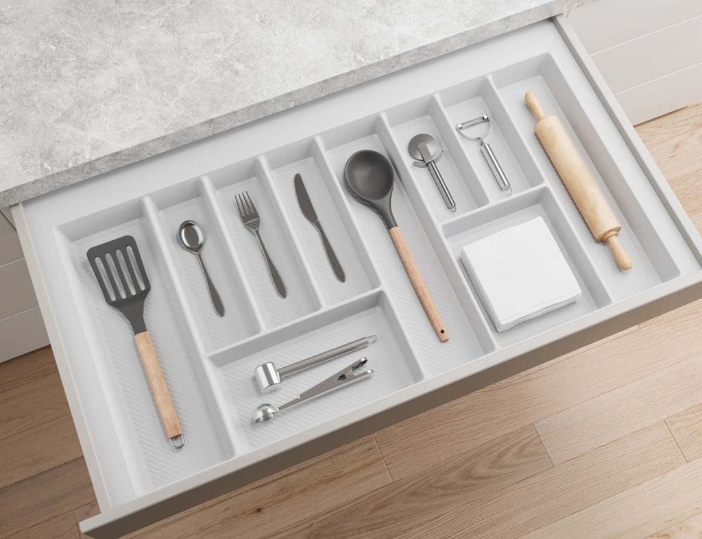 Biały wkład do szuflady kuchennej z przegródkami na sztućce, akcesoria kuchenne i wałek do ciasta.