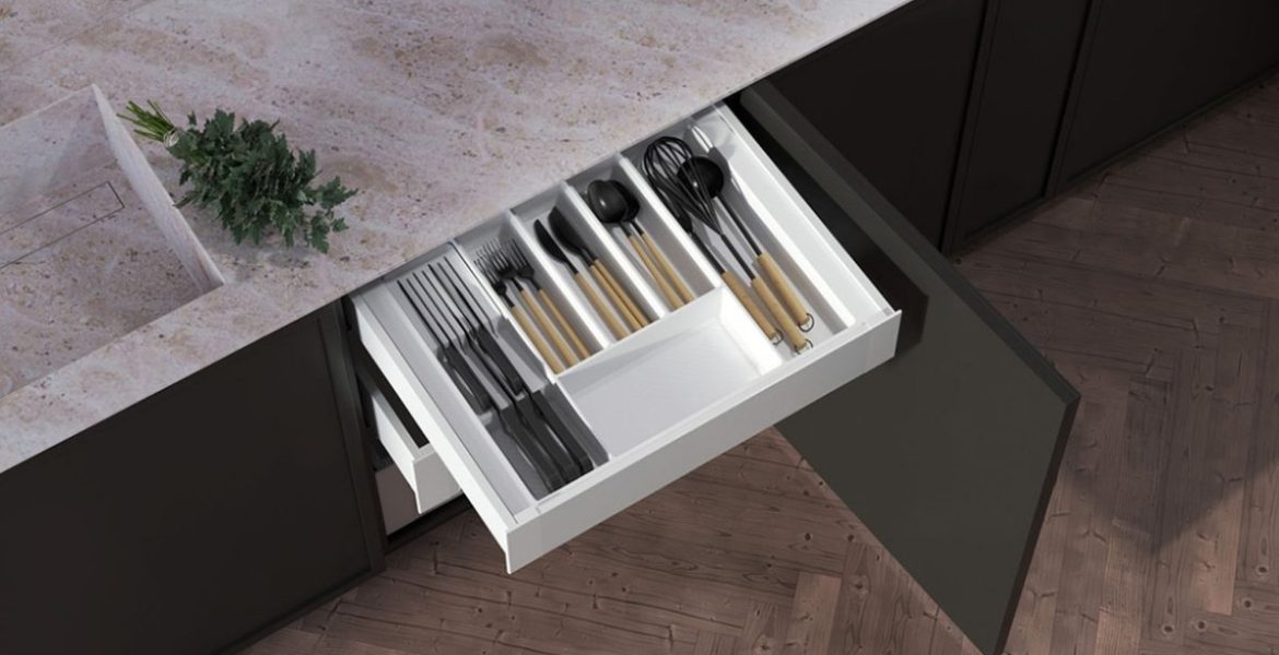 Wkład do szuflady kuchennej typu Ultra Box z organizerem na noże i sztućce, zamontowany w czarnej zabudowie kuchennej.
