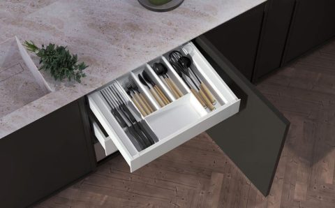 Wkład do szuflady kuchennej typu Ultra Box z organizerem na noże i sztućce, zamontowany w czarnej zabudowie kuchennej.
