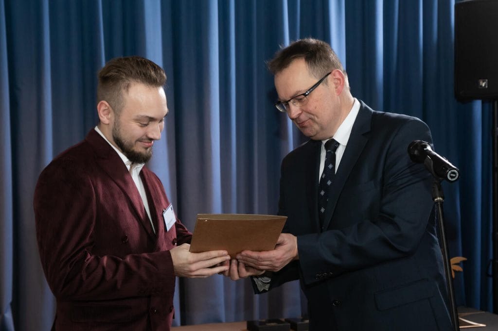Mateusz Nierzwicki, czyli laureat kategorii młody design, odbiera nagrodę za U Chair z rąk Marka Hryniewickiego. Fot. Tomasz Markowski.