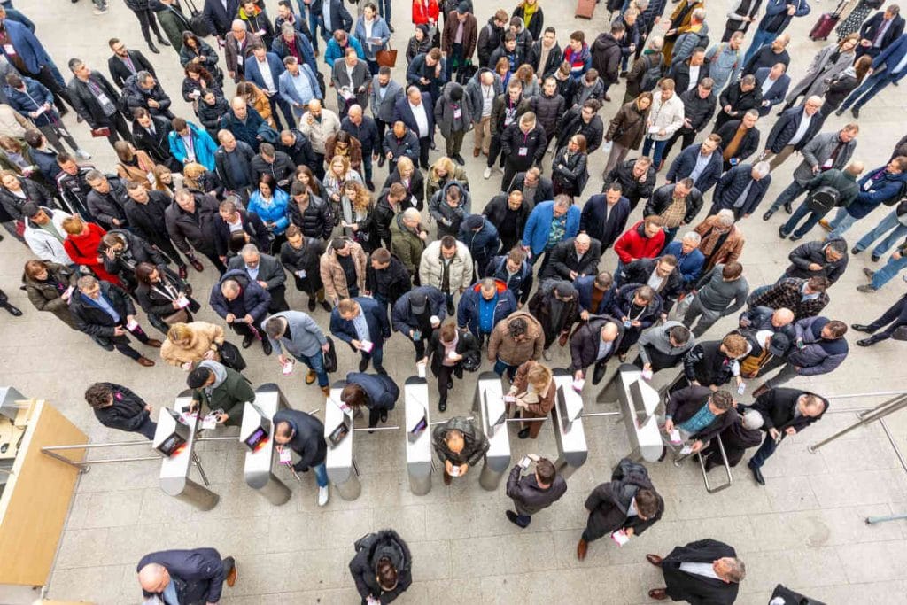 Wysoki widok na tłum profesjonalistów z branży meblarskiej wchodzących na teren targów poprzez bramki kontrolne, co podkreśla duże zainteresowanie wydarzeniem Meble Polska.