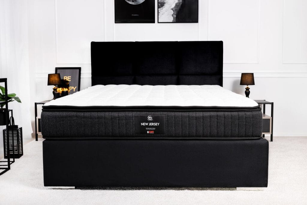 Materac New Jersey Pan Materac to doskonałe połączenie nowoczesnych technologii i najwyższej jakości materiałów. Wyposażony w piankę AF D50 Hyper dla lepszej cyrkulacji powietrza oraz redukcji nacisku, a także elastyczną piankę Hyper D26, idealnie dopasowuje się do sylwetki. System sprężyn kieszeniowych zapewnia optymalne podparcie kręgosłupa i indywidualną reakcję na nacisk. Dodatkowy pillow topper zwiększa miękkość i komfort. To gwarancja zdrowego, regenerującego snu w każdej pozycji. Na zdjęciu: materac hybrydowy New Jersey Pan Materac, łóżko kontynentalne Rif New Concept.