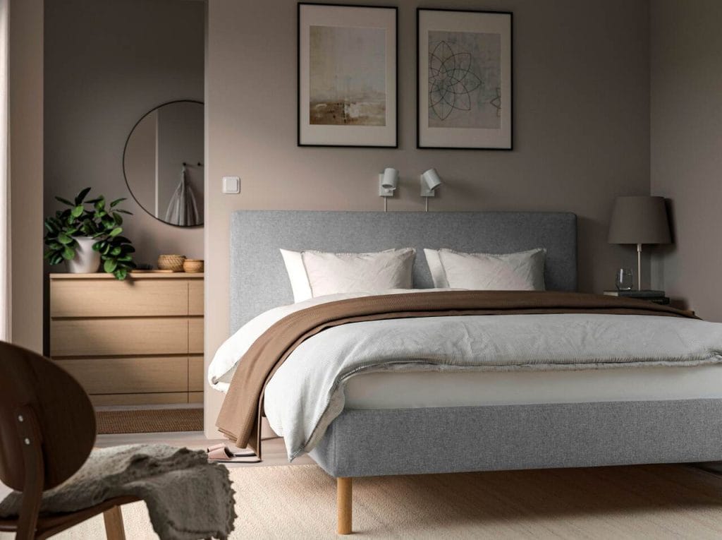 Łóżko TARNKULLEN od IKEA to przykład nowoczesnego podejścia do tapicerowanych ram, które łączą estetykę z funkcjonalnością. Miękka, ciasno dopasowana tkanina Tibbleby wykonana w 90% z poliestru z recyklingu wyróżnia się subtelnym wzorem w jodełkę i lekkim połyskiem. Łóżko harmonijnie wpisuje się w trendy, które promują uporządkowane, przytulne otoczenie sprzyjające spokojnemu snu. Wyściełane wezgłowie zapewnia wygodę podczas relaksu, a możliwość prania pokrycia gwarantuje świeżość przez długi czas. Otwarte dno łóżka ułatwia cyrkulację powietrza, co pomaga utrzymać materac w idealnym stanie przez lata. Dzięki solidnym dębowym nogom konstrukcja jest lekka, a jednocześnie stabilna.