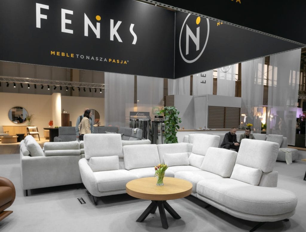 Biały narożnik ze stolikiem na stoisku firmy Feniks na targach Meble Polska 2025 w Poznaniu.