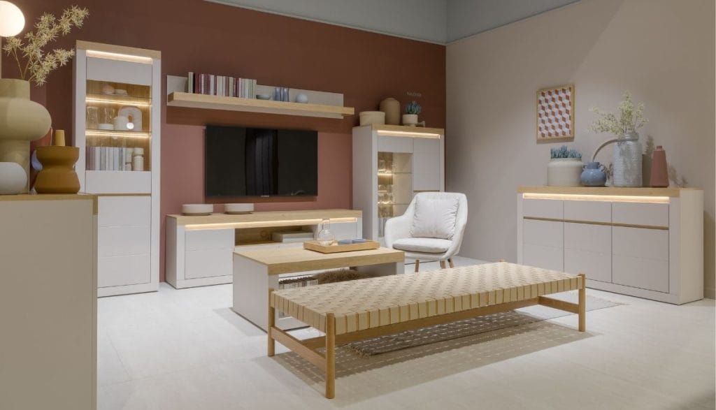 Jasna aranżacja salonu z białymi witrynami LED i rattanową ławką, zaprezentowana na targach Meble Polska 2026 przez Meble Wójcik 40 lat.