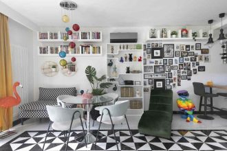 Ten eklektyczny salon łączy różnorodne style i tekstury, tworząc dynamiczną przestrzeń. Wzrok przyciąga biało-czarna podłoga, która kontrastuje z intensywnymi kolorami mebli. Ściany zdobią liczne zdjęcia mieszkańców, nadające wnętrzu osobisty charakter. Całość pobudza zmysły i inspiruje do twórczego działania.