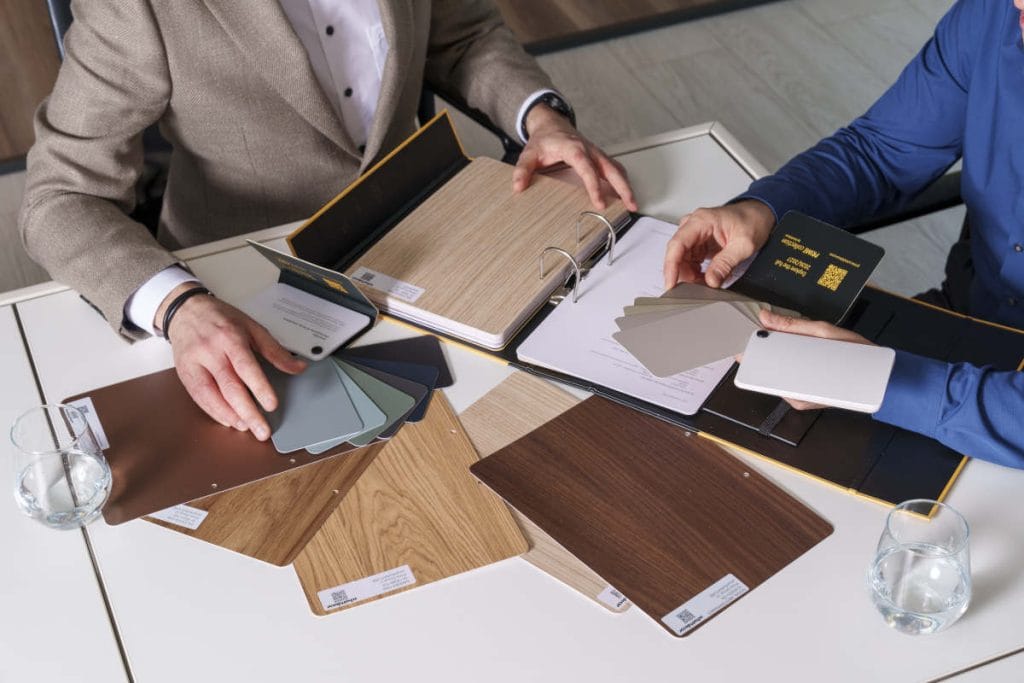 Schattdecor - próbki dekorów wyłożone na stole i oglądane przez dwie osoby 