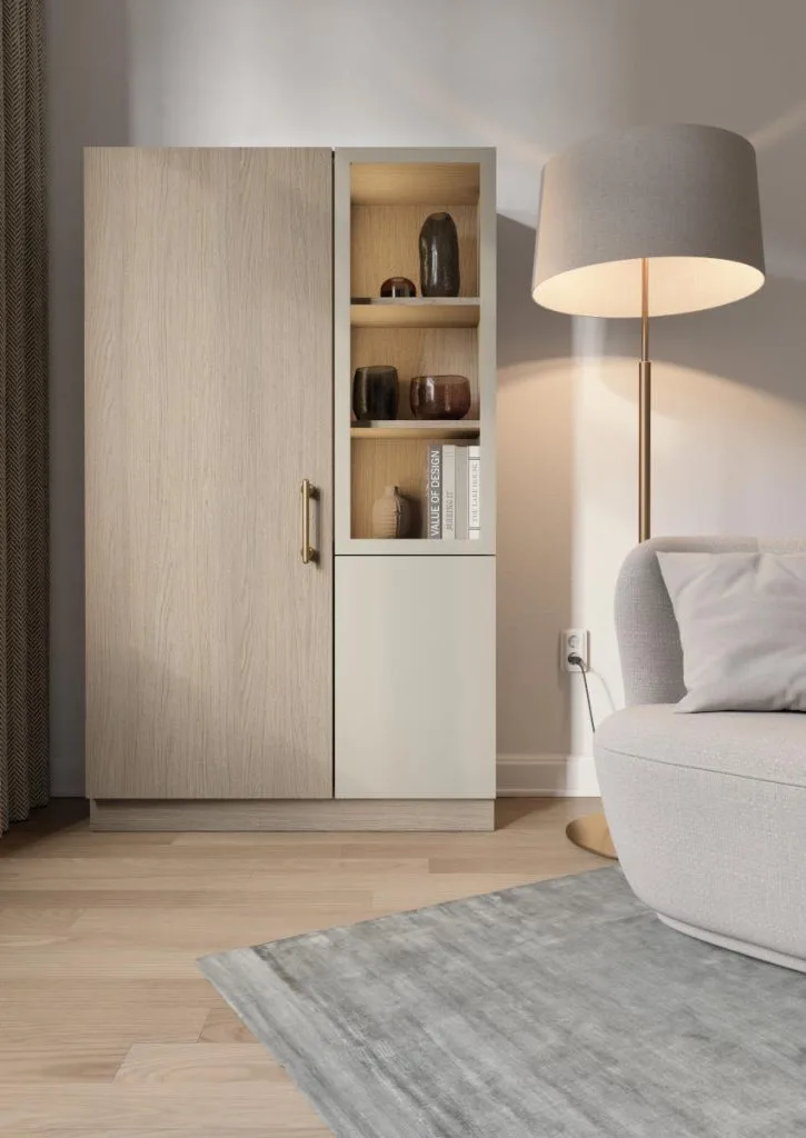 Dwudrzwiowa szafa z witryną łącząca dekor Arles Oak z beżowym frontem. Elegancki mebel salonowy przy jasnoszarej sofie.