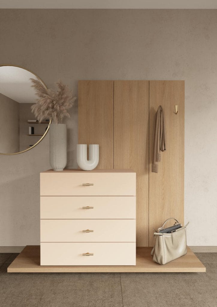 Zabudowa przedpokoju w dekorze Lindberg Oak marki Schattdecor. Zestawienie drewnianych paneli ściennych z jasną, kremową komodą i złotymi uchwytami.