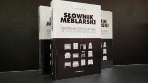 „Słownik meblarski. Materiałoznawstwo nie tylko dla profesjonalistów”, Trzy stojące książki na ciemnym tle..