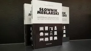 „Słownik meblarski. Materiałoznawstwo nie tylko dla profesjonalistów”, Trzy stojące książki na ciemnym tle..