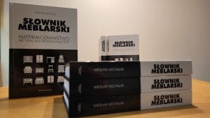 „Słownik meblarski. Materiałoznawstwo nie tylko dla profesjonalistów”, Trzy stojące egzemplarze leżące na stole (od strony grzbietów. Dwa egzemplarze stojące w tle.
