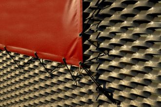 Fragment mebla ogrodowego z rattanu zakryty bordową plandeką.