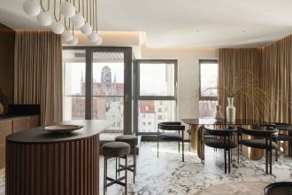 Przykład wnętrza, w którym salon i kuchnia są połączone. Wnętrze apartamentu zlokalizowanego w centrum Wyspy Spichrzów w Gdańsku z widokiem na Długie Pobrzeże i Motławę. Bardzo nowoczesny budynek, ale położony w zabytkowej tkance miasta był ogromnym wyzwanie dla projektanta. Efekt finalny podkreśla tożsamość miejsca, uzupełnieni je, ale nie konkuruje z nim. Projekt: arch. Aleksandra Grzonka, Cechownia. Fot. Tom Kurek.