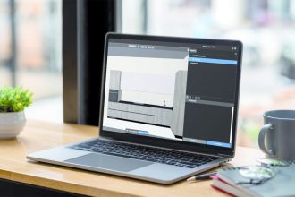 Laptop z oprogramowaniem Viyar Pro na drewnianym biurku obok kubka z kawą i okularów.