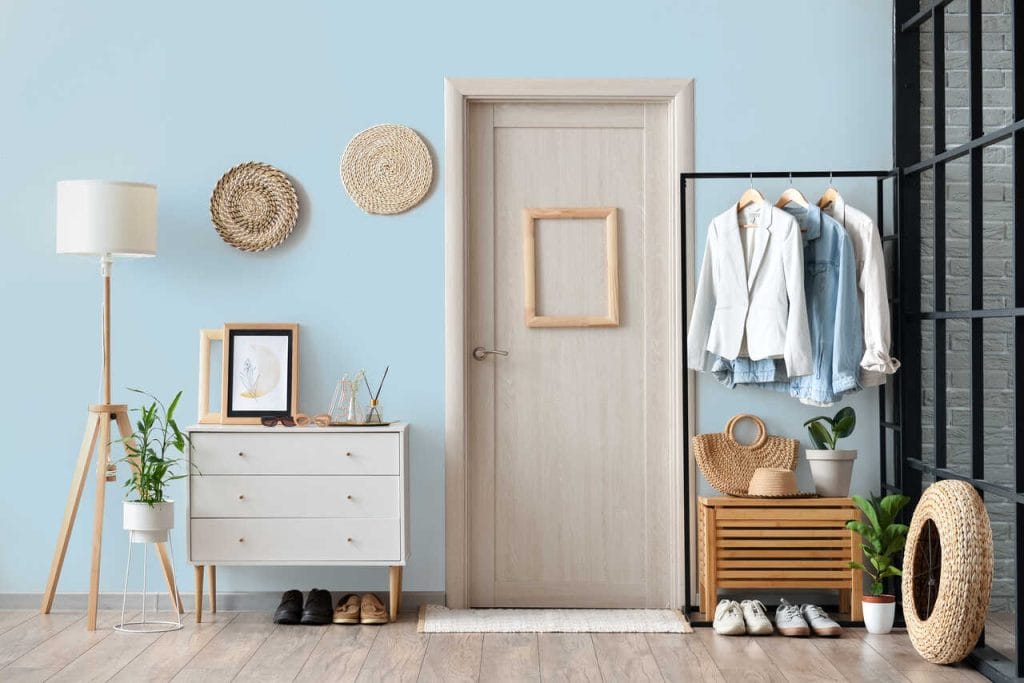 W przedpokoju warto postawić na farbę o wysokiej funkcjonalności – plamoodporną oraz w najwyższej klasie odporności na zmywanie czy szorowanie na mokro, jak Dekoral Effect 3in1. Odcień Błękitny rozjaśni przestrzeń i pozwoli wyeksponować meble z jasnego drewna, które w zestawieniu z plecionkami zbudują przytulną atmosferę od samego wejścia. Wizualną kontrę w takim otoczeniu stworzy nowoczesny wieszak z czarnej stali.
