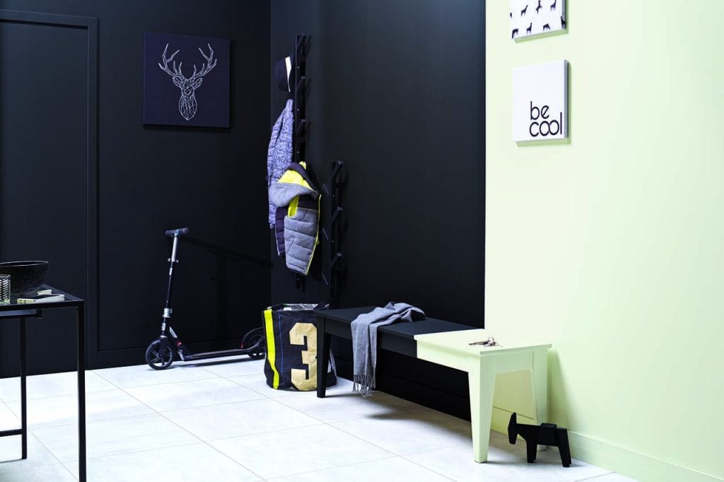 Sposobem na oddzielenie strefy wejścia od reszty domu jest przełamanie czarnym kontrastem Y497 Toro ściany w świetlistej zieleni F390 Horseradish z palety Tikkurila Optiva Satin Matt 7. Pomalowanie należącej do obu części pomieszczenia ławki na dwa te same kolory z wykorzystaniem emalii Tikkurila Everal Aqua pozwoli wykreować zaskakujący i zabawny efekt, zachęcający do obejrzenia reszty domu. Czarne dodatki zapewnią kolorystyczne połączenie obu stref.