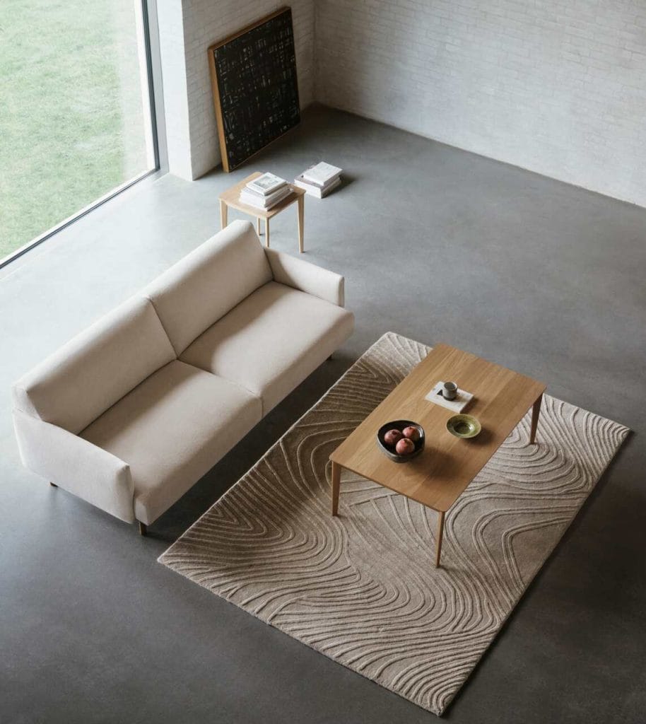 Kolekcja Aarhus od BoConcept to esencja nowoczesnego duńskiego designu, zaprojektowana przez studio ARDE z myślą o funkcjonalności, estetyce i zrównoważonym podejściu. Składa się z eleganckiej sofy, pufy oraz stolików, które wyróżniają się zaokrągloną drewnianą ramą w kolorze naturalnego lub ciemnego dębu. Ich kompaktowe wymiary i lekka forma sprawiają, że idealnie pasują do małych wnętrz, oferując poczucie zorganizowanego komfortu. Kolekcja została zaprojektowana zgodnie z zasadami cyrkularnego wzornictwa – każdy element można łatwo naprawić, wymienić lub poddać recyklingowi, co znacząco wydłuża jego żywotność. Aarhus to połączenie ponadczasowej elegancji z praktycznym podejściem do aranżacji nowoczesnego domu.