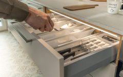 Detal otwartej szuflady kuchennej z wkładem na sztućce, oświetlonej od góry dyskretną listwą LED Loox5. Światło precyzyjnie doświetla zawartość szuflady, ułatwiając znalezienie przyborów kuchennych.