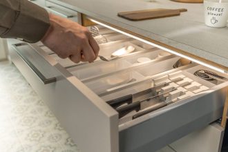 Detal otwartej szuflady kuchennej z wkładem na sztućce, oświetlonej od góry dyskretną listwą LED Loox5. Światło precyzyjnie doświetla zawartość szuflady, ułatwiając znalezienie przyborów kuchennych.