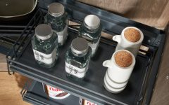 Detal górnej półki cargo AMIX z matą antypoślizgową. Na półce ustawione szklane słoiki i ceramiczne dozowniki na oliwę w nowoczesnej aranżacji kuchennej.