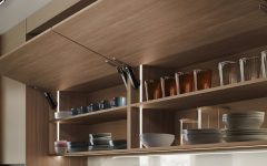 Drewniane szafki kuchenne z systemem bezuchwytowego otwierania Häfele Free Space. Widoczne otwarte fronty typu klapa z dyskretnym mechanizmem podnośnika i podświetleniem LED wnętrza szafek.