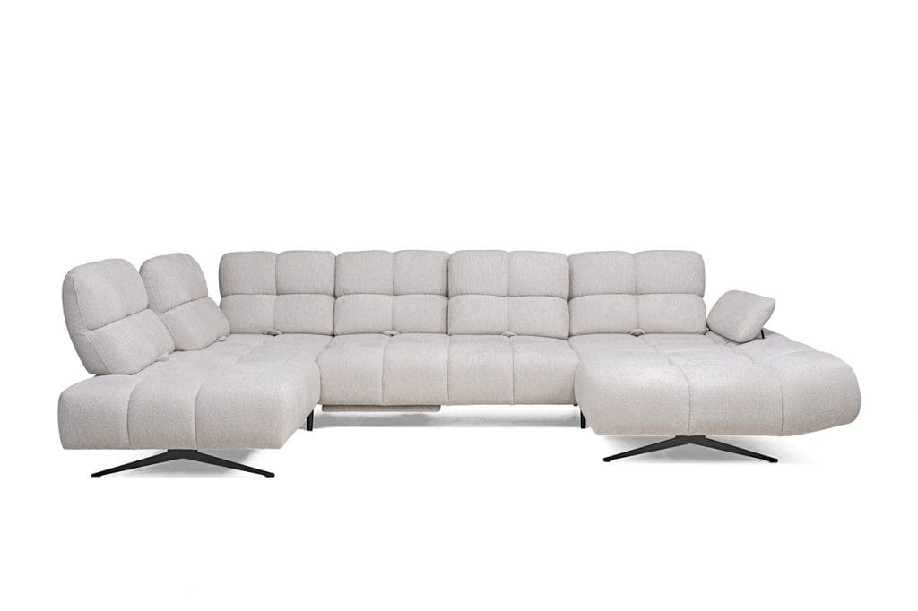 Prado XL to nowoczesny narożnik modułowy z systemu PRADO, łączący elegancję z zaawansowaną funkcjonalnością. Przesuwne i regulowane oparcia umożliwiają zwiększenie głębokości siedziska o 15 cm, zapewniając wyjątkowy komfort. Opcjonalny elektrycznie wysuwany podnóżek oraz stylowe przeszycia podkreślają luksusowy charakter mebla. Dostępny także w wariantach L i S.