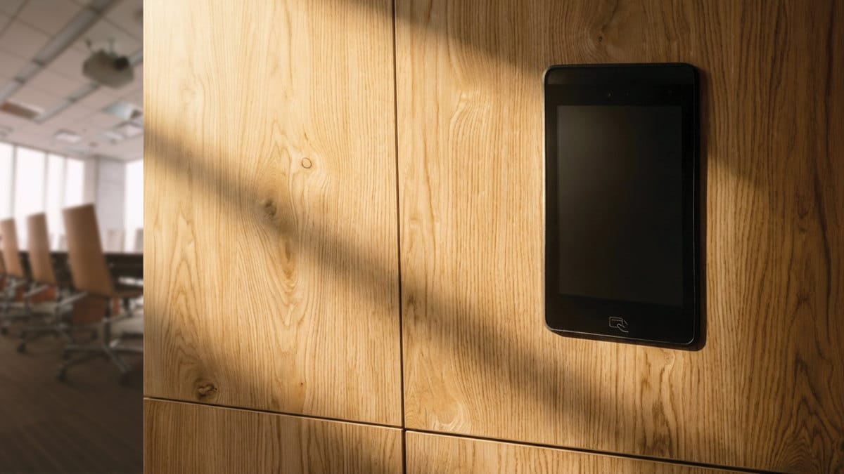 Elektroniczny zamek meblowy z ekranem dotykowym zamontowany w dębowej zabudowie biurowej. Nowoczesne okucia i systemy kontroli dostępu do szafek.