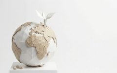 Artystyczna instalacja przedstawiająca globus wykonany z białego i brązowego papieru techniką origami. Z górnej części kuli ziemskiej wyrasta mała, biała papierowa roślina z dwoma listkami, symbolizująca ekologię i zrównoważony rozwój w przemyśle papierniczym.