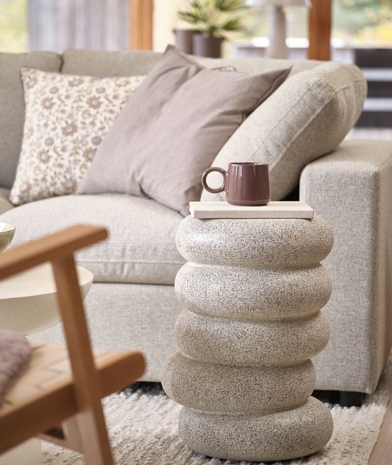 By mocniej wyeksponować dekoracje można sięgnąć po postument GRAM w kolorze trawertynu. Propozycja JYSK idealnie sprawdzi się jako podstawa dla wazonów i świeczników, wydobywając detale na pierwszy plan. Inspirowany naturą postument przywodzi na myśl kamienie ułożone jeden na drugim. Źródło: Biuro prasowe JYSK Polska.