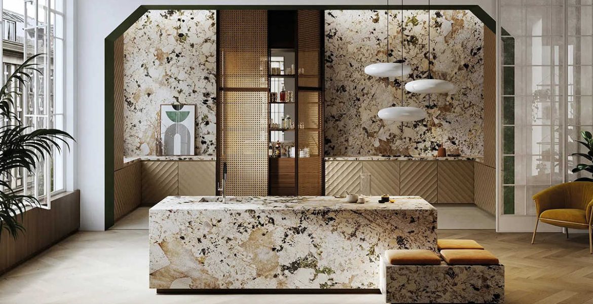 Luksusowa kuchnia z monolityczną wyspą i ścianami wykończonymi wielkoformatowym spiekiem kwarcowym Alpinus White o wyrazistym, kamiennym wzorze w odcieniach bieli, beżu i czerni. Dolne szafki posiadają fronty z pionowym ryflowaniem w kolorze piaskowym, a całość dopełniają nowoczesne, obłe lampy wiszące oraz eleganckie detale z drewna i plecionki wiedeńskiej.