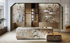 Luksusowa kuchnia z monolityczną wyspą i ścianami wykończonymi wielkoformatowym spiekiem kwarcowym Alpinus White o wyrazistym, kamiennym wzorze w odcieniach bieli, beżu i czerni. Dolne szafki posiadają fronty z pionowym ryflowaniem w kolorze piaskowym, a całość dopełniają nowoczesne, obłe lampy wiszące oraz eleganckie detale z drewna i plecionki wiedeńskiej.