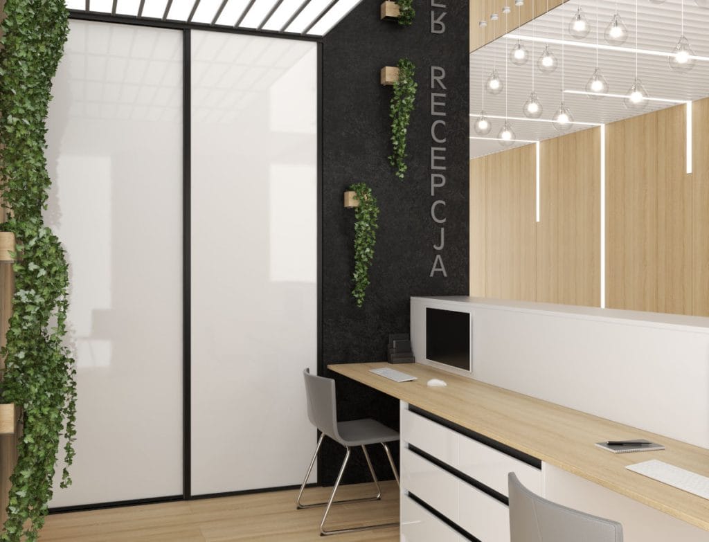 Nowoczesne wnętrze recepcji z biurkiem o jasnym blacie, białymi szufladami i czarną ścianą z napisem "RECEPCJA". Po lewej stronie szafa przesuwna z białymi frontami w czarnych ramkach Sevroll, a w tle dekoracyjna roślinność pnąca.