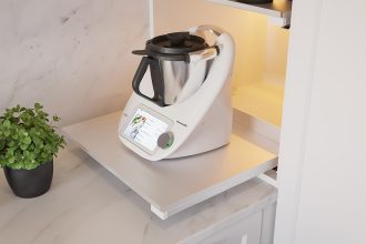 Detaliczny widok wewnętrznej wysuwanej półki REJS Puro w jasnym wykończeniu, z postawionym robotem kuchennym Vorwerk Thermomix i ziołami, na tle marmurowego blatu.