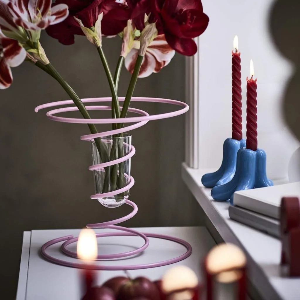 W zimowej kolekcji IKEA VINTERFINT 2025 niemal całą uwagę skradł wazon. Jego sprężynowa, metalowa konstrukcja skrywa szklaną wkładkę. Nieoczywista forma łączy w sobie lekkość, funkcję i humor. Spiralna rama podtrzymuje kwiaty, jednocześnie nadając całości dynamiczny charakter. [[Okrągła forma nie ma końca, co daje przedmiotowi więcej życia. Ten wazon jest tego przykładem – jego kształt jest nieprzerwany, a przy tym wnosi element zabawy dzięki swojej sprężystości. To połączenie dwóch części, które pozornie nie potrzebują siebie nawzajem, a jednak razem tworzą pełnię – jak dwie części układanki]] – wyjaśnia Gustaf Westman. Fot. Biuro prasowe IKEA Polska.
