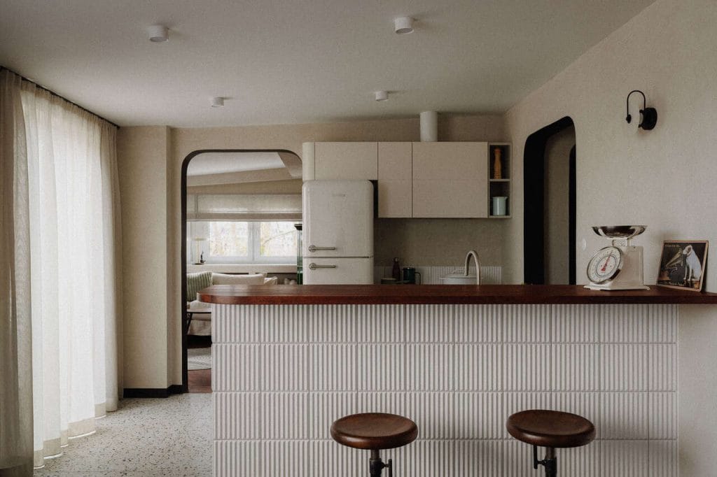 Apartament na ostatniej kondygnacji modernistycznej kamienicy w Gdyni. Ściany pokryto tynkiem strukturalnym, podłoga to parkiet przemysłowy. Dominują naturalne materiały, trochę retro: lastryko, ryflowane kafle, len, tapety obiektowe. Do tego dochodzą – jako akcenty – mocne kolory i wzory, np. zielony kominek. To wnętrze spokojnie, a jednocześnie odważnie. Proj. Ossowska. architektura wnętrz. Zdjęcia  - FotoMohito.