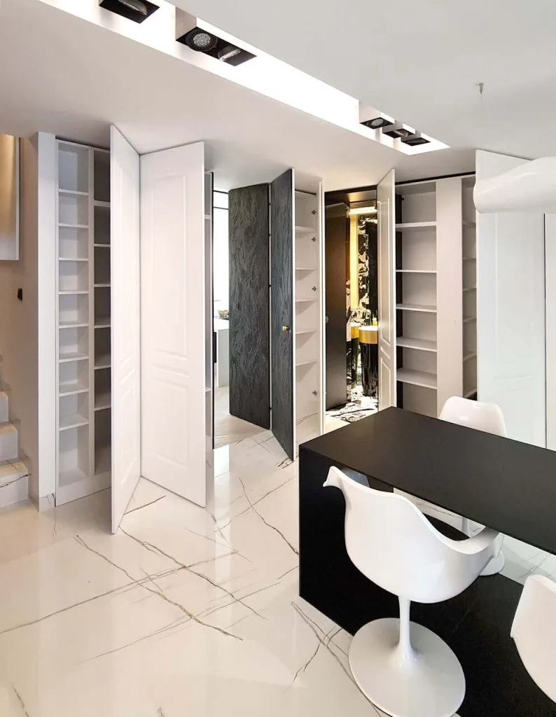 Luksusowy apartament dwupoziomowy o powierzchni ok. 140 m2 przeznaczony pod wynajem dla klienta premium, zlokalizowany w prestiżowej enklawie Magnoliowe Ogrody na Woli Justowskiej w Krakowie. Jako że oryginalny układ mieszkania nie spełniał wymagań inwestora, wyburzono wszystkie ścianki działowe na dolnym poziomie i zaprojektowano całkowicie nową aranżację pomieszczeń. W nowej aranżacji podziały w 90% zrealizowano przy użyciu wyłącznie zabudowy meblowej. Każdy z frezowanych paneli tworzących ściany jadalni połączonej z kuchnią i salonem po otwarciu odkrywa inną tajemnicę: regały, szafy, wejście do gabinetu, łazienki i schowka gospodarczego. Projekt i realizacja: Swałtek Design Studio.