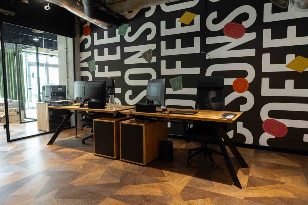 Przestrzeń dla Coffee & Sons została zaprojektowana jako nowoczesne i komfortowe środowisko pracy, w którym kluczową rolę odgrywają naturalne materiały, stalowe konstrukcje i minimalistyczne wzornictwo. Centralnym elementem aranżacji, zrealizowanej przez Deerhorn, są biurka wykonane z naturalnego drewna i osadzone na stalowych stelażach, łączące wysoką trwałość z ponadczasową estetyką. Zastosowanie drewna ociepla wnętrze i nadaje mu przyjazny charakter, a ergonomiczny układ oraz funkcjonalne rozwiązania sprzyjają zarówno codziennej pracy, jak i spotkaniom zespołowym. Projekt harmonijnie łączy estetykę, funkcjonalność i komfort użytkowania, odpowiadając na potrzeby nowoczesnego biura.