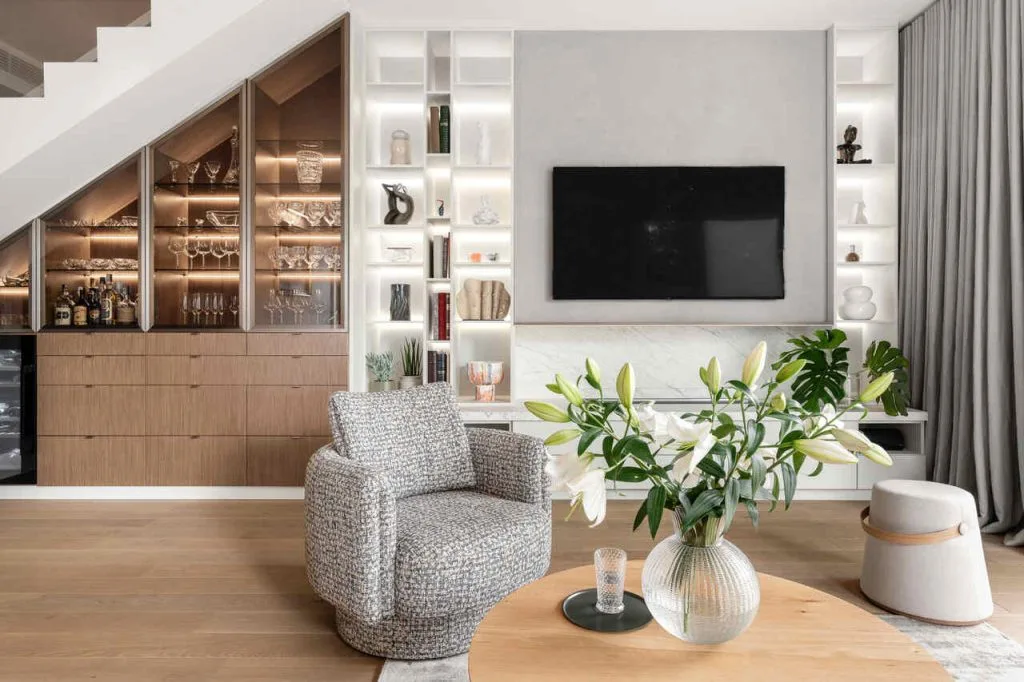 Apartament, w którym minimalizm łączy się z funkcjonalnością. Hol łączy w sobie komunikację, ukrytą szafę na ubrania, a także wejście do łazienki i sypialni. Jednocześnie zabudowa jest częścią kuchni, którą oddziela od holu. Ścianę dzielącą hol od schodów pokryto listem, które odbija światło z okien kuchni i powiększa tę dość wąską przestrzeń. Druga ściana, oddzielająca kuchnię od salonu, chowa w sobie wysoką zabudowę kuchni, wokół której jest przejście z dwóch stron: stąd do kuchni można przejść od strony holu i bezpośrednio przy ścianie z salonu. Proj. Ossowska. architektura wnętrz, Casadeideas. Magdalena Gzowska. Fot. Fotomohito.
