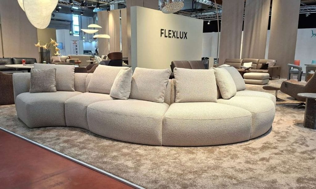 ALT: Modułowa sofa półokrągła z tkaniny bukle w jasnym kolorze na stoisku Flexlux podczas M.O.W. 2026.